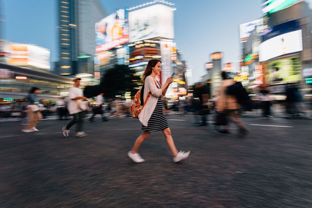 Woman walking through busy city while checking her investments on the Shyft app