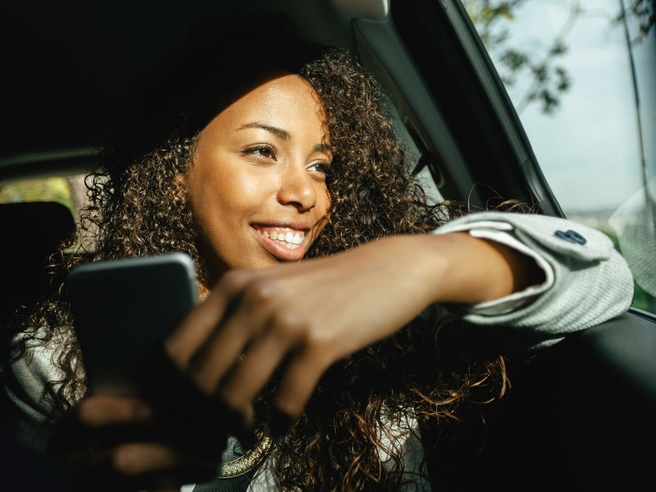 Woman smiling in car with her phone