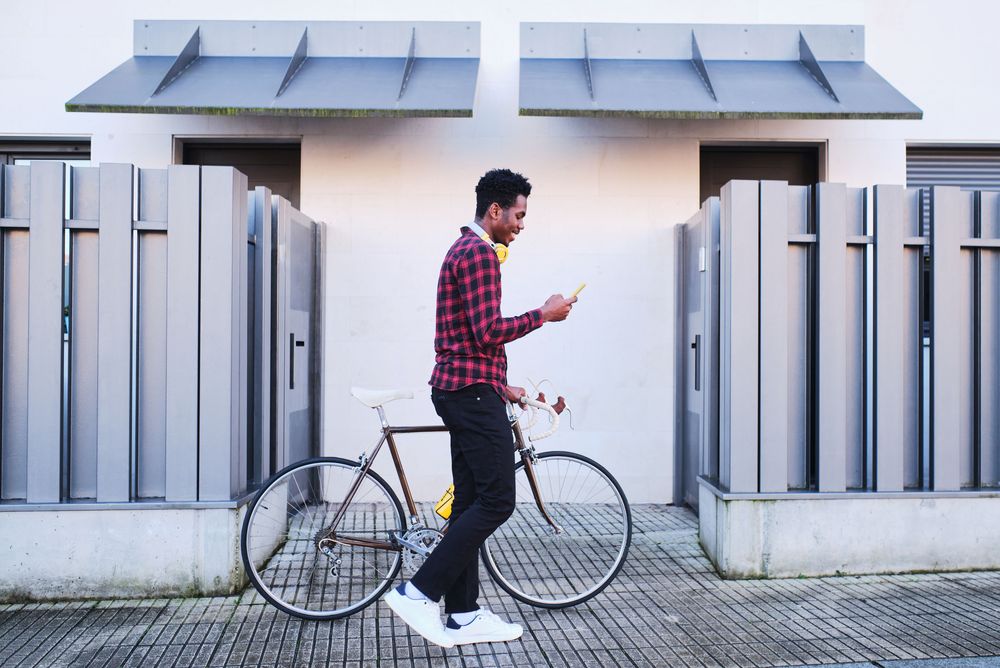Young man with a bicycle checking his investments on his cellphone